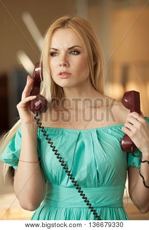 pretty blonde woman in green dress talking on old telephone. Fashion model. Sunny color.