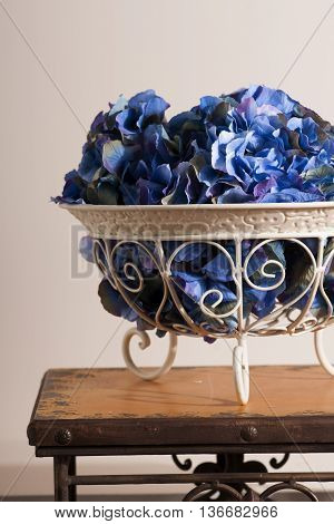 flowers of blue hydrangeas in a metal florid forged vase on stools