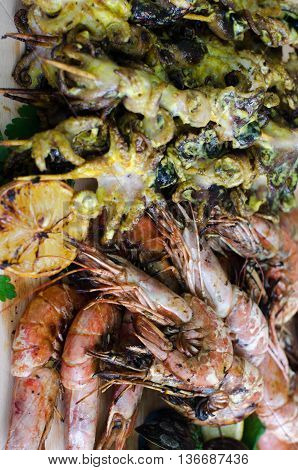 Grilled seafood (shrimps and squids) on wooden sticks for a bbq (barbecue) party