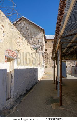 FREMANTLE,WA,AUSTRALIA-JUNE 1,2016:  Fremantle Prison outdoor boundary courtyard walls with razor wire under a blue sky in Fremantle, Western Australia.