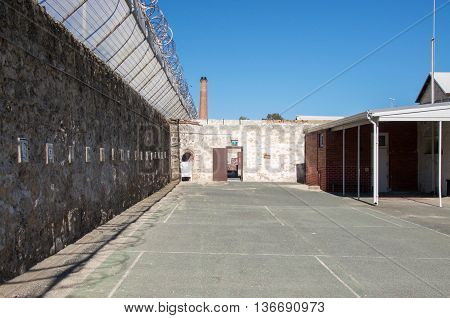 FREMANTLE,WA,AUSTRALIA-JUNE 1,2016:  Fremantle Prison with limestone brick walls and razor wire under a blue sky in Fremantle, Western Australia.
