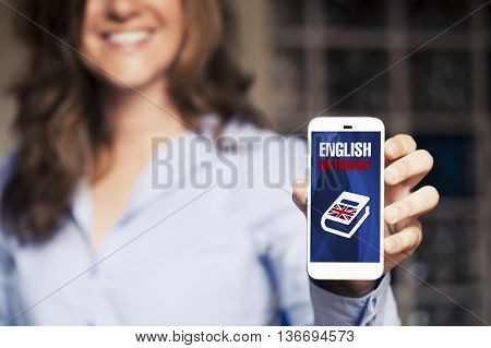 Smiling woman holding smart phone with english dictionary application in the screen.