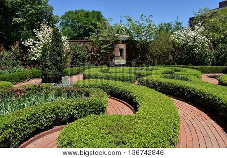 New Bern North Carolina - April 24 2016: Clipped Boxwood hedges line brick pathways in the Maude Moore Latham Memorial Knot Garden at 1770 Tryon Palace