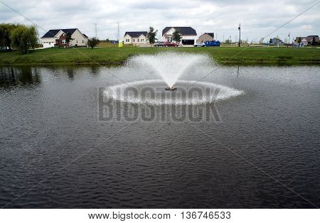 SHOREWOOD, ILLINOIS / UNITED STATES - AUGUST 30, 2015:  A fountain helps to aerate water in a small lake near the Village of Shorewood Village Hall.