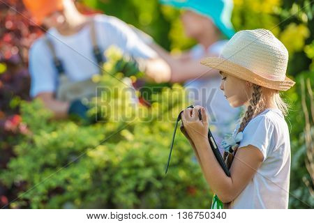 Children and the Internet. Little Girl Playing with Her Tablet Device in the Garden While Parents Working in the Background. Parental Control Conceptual Photo.
