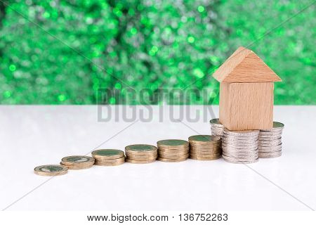 Wooden block houses and coin stacks in a row with a green background
