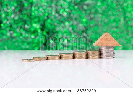 Wooden block houses and coin stacks in a row with a green background
