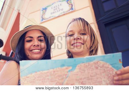 Female friends on holiday young latina women having fun traveling. Two happy girls smiling in Havana Cuba using city map for directions.