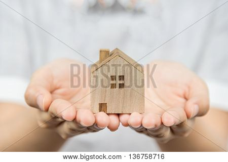 Woman presenting wooden house model in her hand real estate concept.