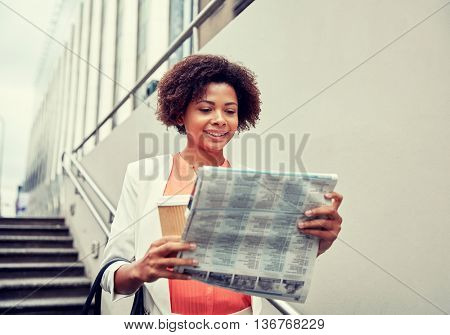 business and people concept - young smiling african american businesswoman with coffee cup going down stairs into city underpass