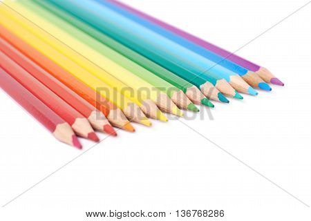 Multiple colorful color pencils composition arranged in a line to form a rainbow gradient, composition isolated over the white background, close-up crop fragment