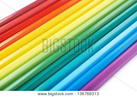 Multiple colorful color pencils composition arranged in a line to form a rainbow gradient, composition isolated over the white background, close-up crop fragment