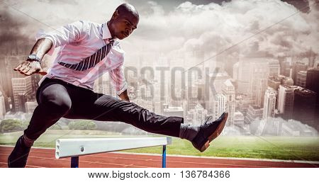 Businessman jumping a hurdle against composite image of track against city