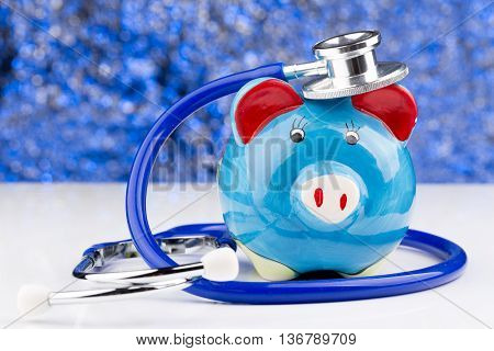 Close up of a stethoscope with a piggy bank
