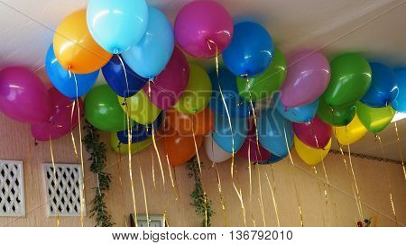 Multi-colored balloons tied ribbons on holiday hanging from the ceiling