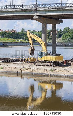 Yellow excavator on the construction site to build a new bridge.