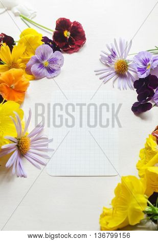 A white sheet of paper on the white background surrounded with colourful flowers