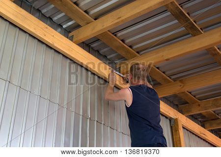Work takes measurements on the ceiling beam