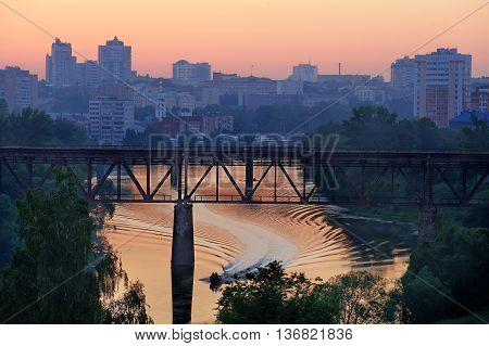 Railway bridge the bridge over the river boat racing at twilight horizontal