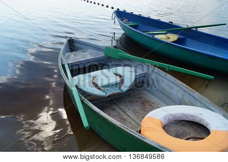 green and blue boats on the river with oars and a lifeline