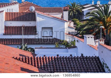 Chalets with roofs from terracotta tiles beside Mediterranean Sea. Top view. Summer vacations concept. Horizontal.