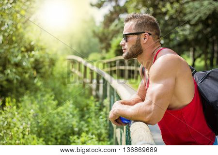 Handsome Muscular Hunk Man Outdoor in City Park, During Daytime, Wearing Tanktop and Sunglasses