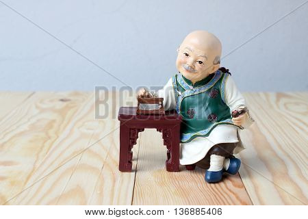 Happy Grandfather In Chinese Doll Is Listening Music On  Wood Background