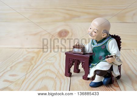 Happy Grandfather In Chinese Doll Is Listening Music On  Wood Background