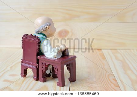 Happy Grandfather In Chinese Doll Is Listening Music On  Wood Background