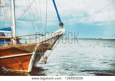 Boat moored at the sea pier. Wooden boat in the sea on a background of blue sky with clouds