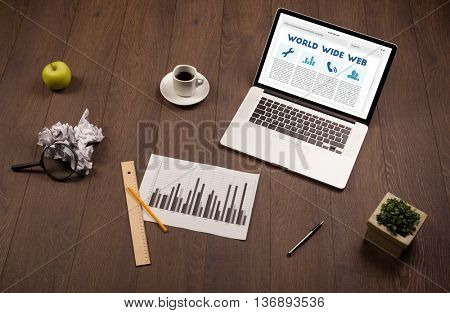 Laptop computer on wooden desk with office suplies