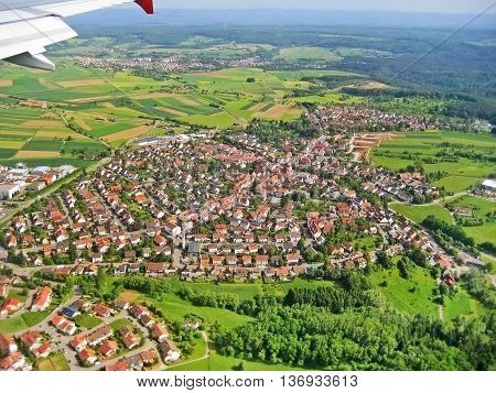 Typical german village during landing approach surrounded by fields and forest aerial view