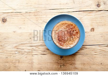 Cappucinno on a wooden cafe table viewed from above