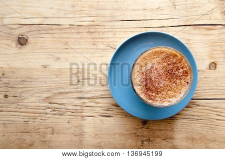 Cappucinno on a wooden cafe table viewed from above