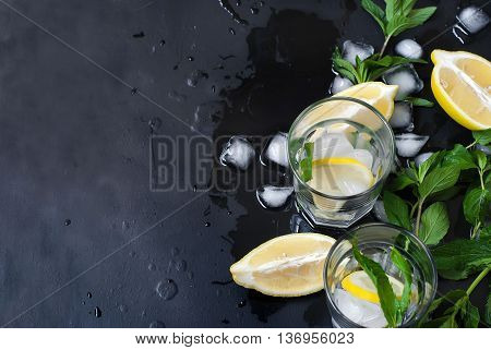 Ingredients for lemonade or long drink mint leaveslemon ice cubes on wet black background top view