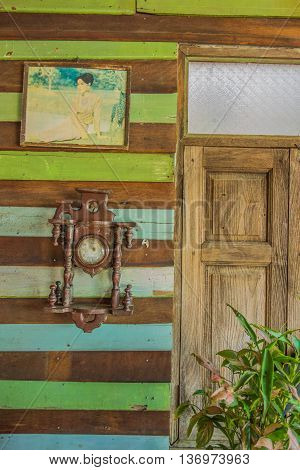 KANCHANABURITHAILAND-JUNE 30:Antique clock is hang on the wooden wall on June 302016 in ThamuangKanchanaburiThailand.The old picture of thai queen also.