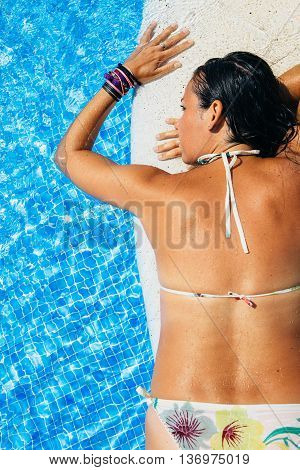 View on brunette woman in bikini on board in swimming pool.From above