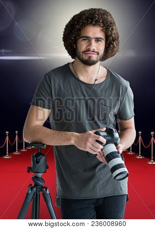 photographer rest on tripod, with the camera on hands in the red carpet. Flares behind