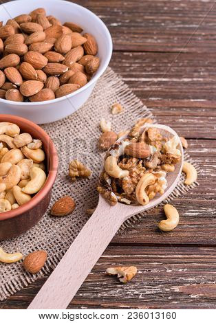 Differrent Variety Of Nuts - Walnuts, Cashew, Almond In Bowls And Wooden Spoon. Rustic Scratched Woo