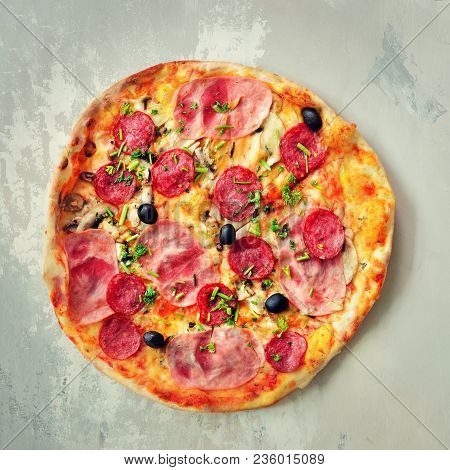 Fresh Italian Pizza With Mushrooms, Ham, Tomatoes, Cheese, Olive, Pepper On Grey Concrete Background
