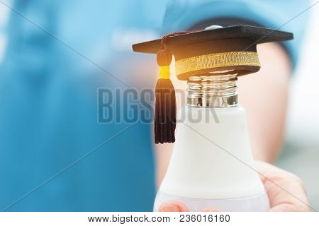Graduate Study, Education Knowledge Power Concept: Hands Holding Light Bulb With Graduated Cap. Conc