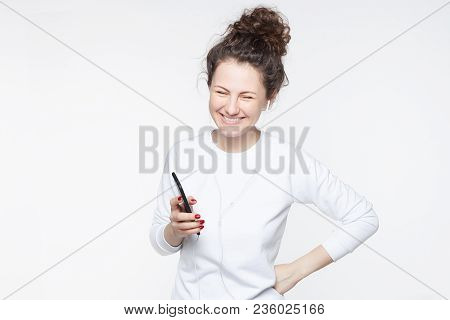 Happy Young Caucasian Female Model With Broad Smile, Laughs Joyfully As Hears Anecdotes Online In He