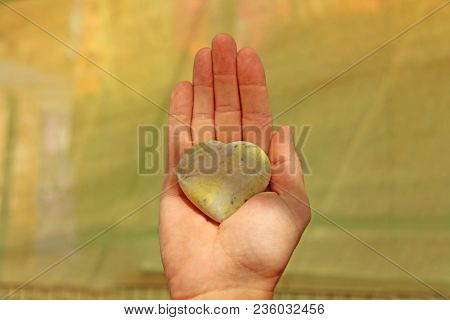 The Hand Holds A Heart Made Of Natural Stone Yellow Jadeite. Heart In Hand. A Stone In The Shape Of 