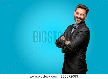 Middle age man, with beard and bow tie with crossed arms confident and happy with a big natural smile laughing
