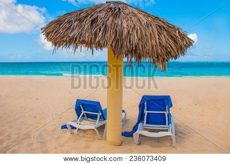Holguin, Cuba, Playa Esmeralda. Umbrella And Two Sun Loungers Are On The Sand. Tropical Beach On The