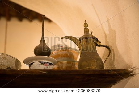Antique arabic utensils- Antique Arabic Dallah and other traditional utensils are displayed on the shelf.