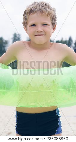 Boy In Inflatable Ring Standing On The Lake Coast. Happy Holidays.