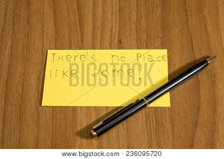 Ther's No Place Like Home Handwrite On A Yellow Paper With A Pen