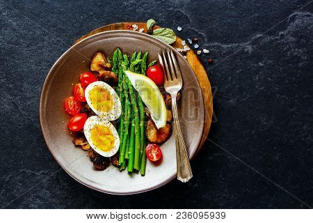 Flat-lay Of Healthy Vegetarian Breakfast Plate. Aspargus, Tomatoes, Mushrooms And Eggs Over Black St