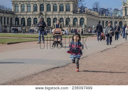 Little Asian Girl Runs Along The Path In Dresden Zwinger, Germany, Dresden, Zwinger 30.03, 2018.